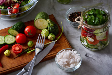 Fresh vegetable salad and ripe veggies on cutting board over white background, close up, selective focus