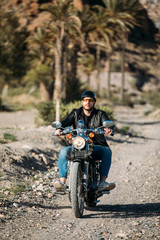 Fototapeta na wymiar young man driving a motorbike in a desert place. lifestyle concept