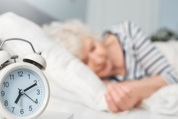 Closeup photo alarm clock. Blurred background sleeping woman