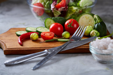 Fresh vegetable salad and ripe veggies on cutting board over white background, close up, selective focus
