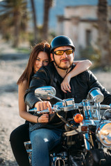 Naklejka na ściany i meble young couple riding a motorcycle and looking at the camera in a desert place. lifestyle concept