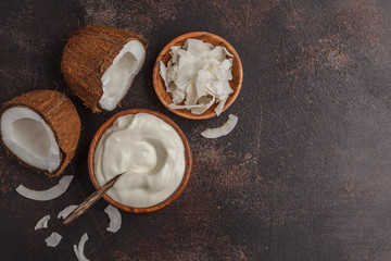 Coconut yogurt in a wooden bowl on a dark background, top view, copy space. Healthy vegan food concept.