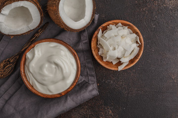 Coconut yogurt in a wooden bowl on a dark background, top view, copy space. Healthy vegan food concept. © vaaseenaa