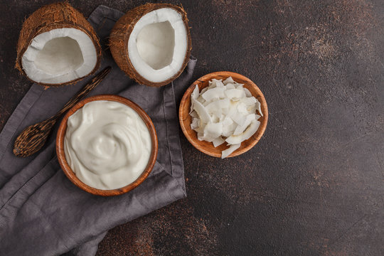 Coconut yogurt in a wooden bowl on a dark background, top view, copy space. Healthy vegan food concept.