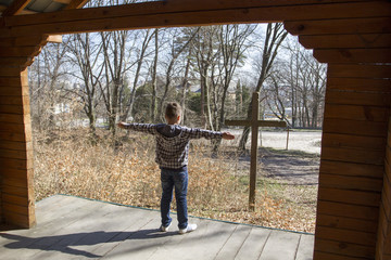 A young man in front of a cross. Cross in the forest.