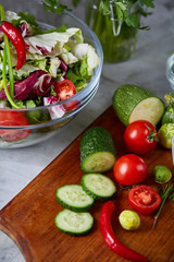 Fresh vegetable salad and ripe veggies on cutting board over white background, close up, selective focus