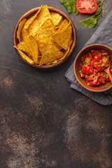 Mexican food concept. Nachos - yellow corn totopos chips with tomato sauce pico del gallo, top view, copy space.