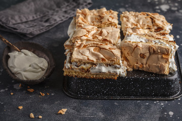 Sliced Norwegian cake with meringue and whipped cream, dark background