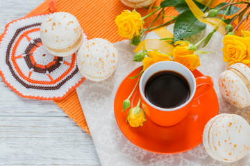 Orange cup of black coffee, yellow roses flowers and sweet paste
