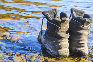  Abandoned Hiking travel shoes on the banks of the river at sunset. Selective focus