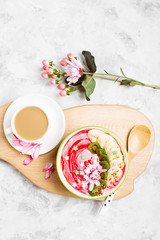 Berry smoothie with kiwi and banana in a bow and cup of coffee  with flowers. Cute breakfast