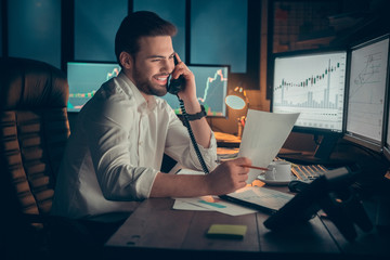 Young male trader at office work concept sitting talking on telephone cheerful