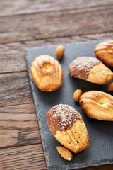Freshly baked almond cookies with almond on stone board over wooden background, top view, selective focus.
