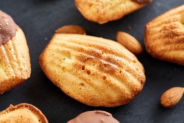 Freshly baked almond cookies with almond on stone board over wooden background, top view, selective focus.