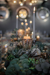 Mirror table served with plates, forks, spoons, glasses,  napkins in the restaurant. Beautiful festive table decorated with fresh flowers and candles