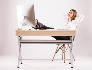 Young attractive successful businesswoman resting her legs on the desk isolated on white
