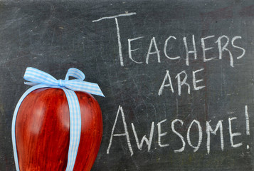 Teacher appreciation image of a red apple tied up with a cute blue ribbon in front of a worn...