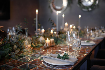 Mirror table served with plates, forks, spoons, glasses,  napkins in the restaurant. Beautiful festive table decorated with fresh flowers and candles
