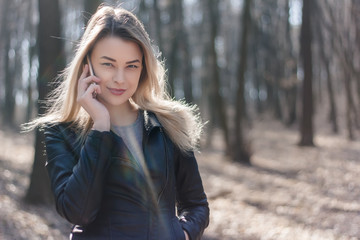 Naklejka premium Happy beautiful woman speaking on a cellphone in the park. Autumn time.