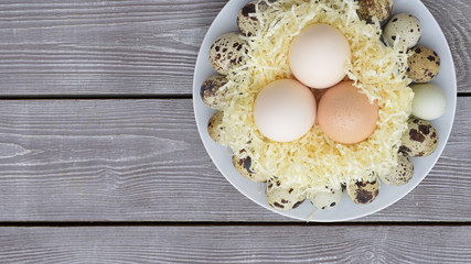 Chicken and quail eggs on wooden background top view