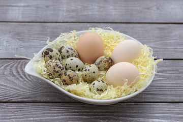 Chicken and quail eggs on wooden background