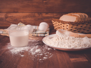 Flour, eggs, milk on a wooden background. Preparation of the dough.