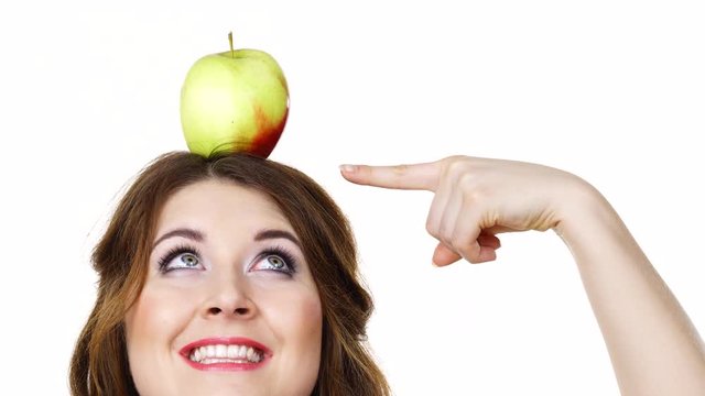 Woman young cheerful female eyes makeup holding big red green apple fruit on head, pointing. Healthy eating, vegetarian food, dieting concept