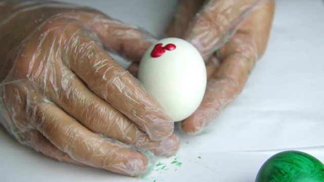 Applying a red paint on an egg