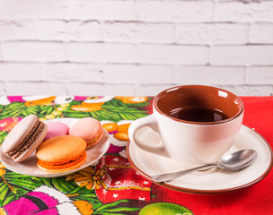 Mug with tea and a plate with French dessert cakes on the table