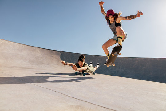 Female skaters doing stunts at skate park