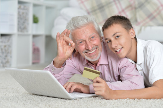 grandfather and grandson using laptop, grandson holding credit c