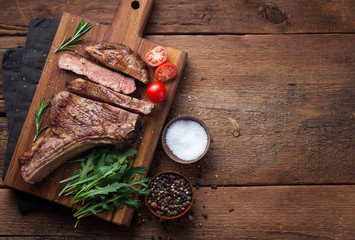 Grilled cowboy beef steak, herbs and spices on a rustic wooden background. Top view with copy space for your text