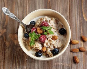 healthy eating and diet concept: Oatmeal porridge in bowl topped with fresh blueberries and raspberries on wooden table