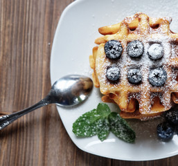 Homemade waffles with blueberries in plate on wooden table
