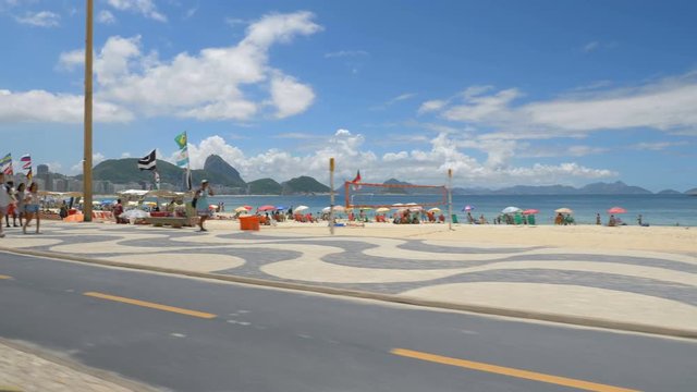 Copacabana Beach on Sunny Day, Rio De Janeiro, Brazil. Driving along the famous mosaic walkway. Slow motion