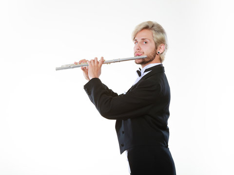 Male flutist wearing tailcoat plays flute