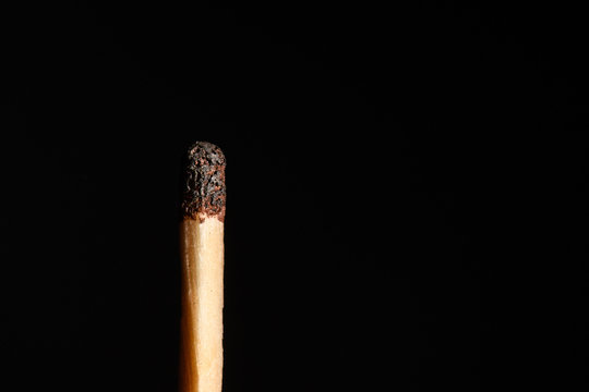Match with half-burned head on a black background closeup