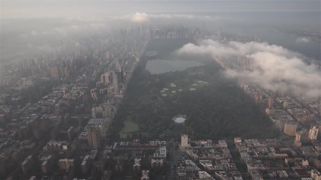 New York City aerial view of Central Park from Harlem, with Upper East Side, Upper West Side and Midtown Manhattan covered in fog and low level clouds at sunrise.