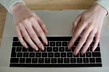 Fototapeta na wymiar Top view of woman hands typing on a computer keyboard. 