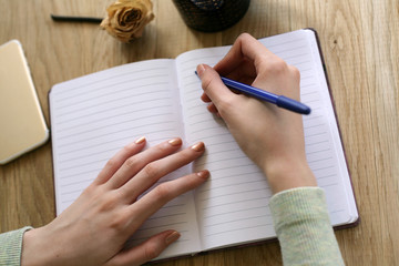 Fototapeta na wymiar Top view of woman hands writing on open notebook .