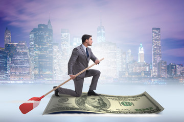 Businessman rowing on dollar boat in business financial concept