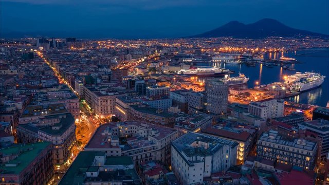 Naples, Italy. Aerial night cityscape with skyline, car traffic, seaport view. Vesuvius on the background. Time lapse. Zoom effect