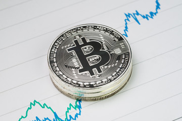 Bitcoin cryptocurrency, digital money price rise concept, stack of physical coins with B sign alphabet on rising price graph on paper