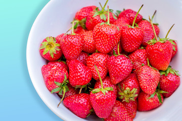 Close up of fresh strawberry in the white bowl on bright background.