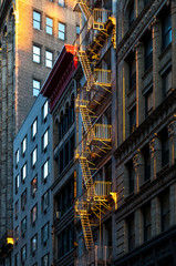 Warm glow of sunlight shining on a fire escape on the front of an old building in New York City