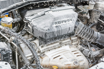 Wash the engine with foam. The engine is in the foam for washing the car. Hoses in the foam.