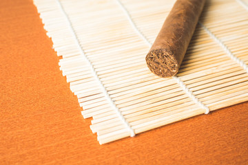 Fragrant cigar on white bamboo mat.
