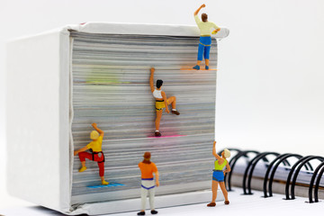 Miniature people climbing book with challenging route on cliff, Concept of the path to purpose and...