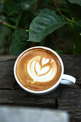a cup of latte art coffee on wooden background