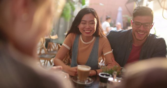 Young multi-ethnic hipster couple having fun with friends at cafe